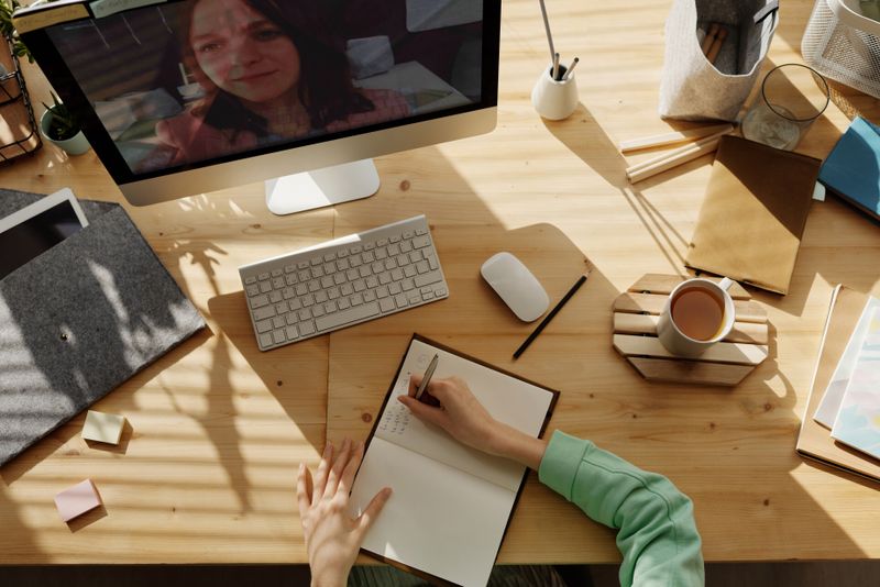 Cuaderno abierto con anotaciones a mano y una laptop al lado sobre un escritorio